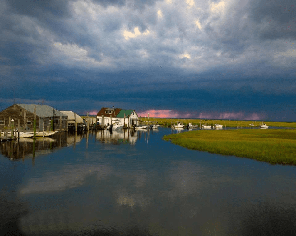 Marsh docks and boats under a stormy sunset sky